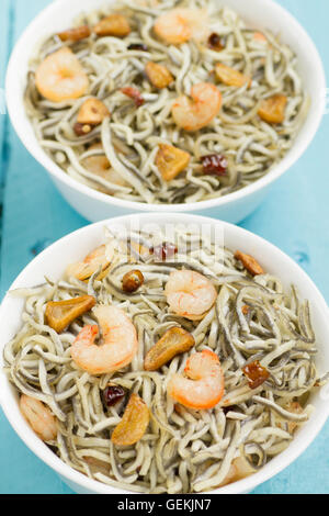 Surimi elvers with prawns, garlic and pepper on two white bowls on a blue wooden table Stock Photo