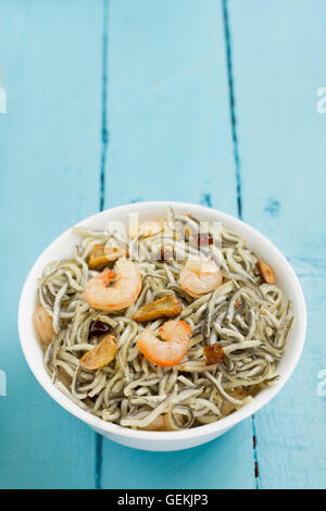 Surimi elvers with prawns, garlic and pepper on a white bowl on a blue wooden table Stock Photo