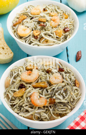 Surimi elvers with prawns, garlic, pepper, bread, fork and napkin on a blue wooden table Stock Photo