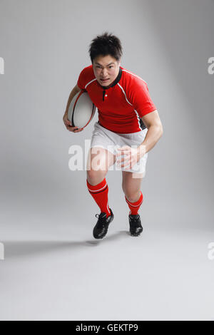 Portrait of Japanese rugby player running with ball Stock Photo