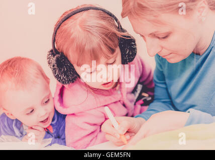 Mother and her children - son and daughter, spending time together doing some activities like drawing and writing Stock Photo