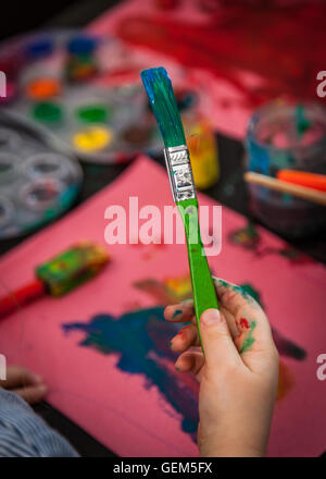Child hand holding dirty brush used for painting pictures at home Stock Photo