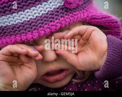 Little girl being very tired and sleepy and rubbing her eyes Stock Photo