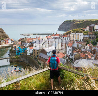 Staithes: male hiker on The Cleveland Way coastal trail overlooking Staithes village on the North Yorkshire coast. England. UK Stock Photo