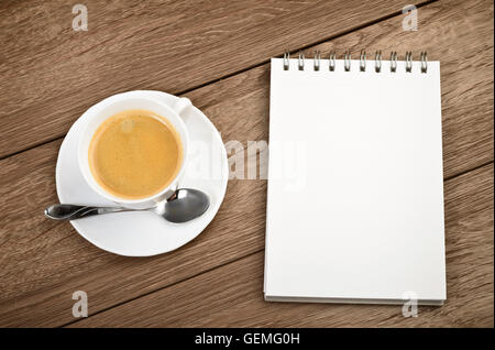 Top view Cup of coffee in a white cup and spiral notepad on wooden background Stock Photo