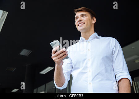 Cheerful young businessman using mobile phone and smiling Stock Photo