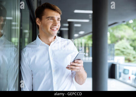 Cheerful young businessman waiting and using cell phone Stock Photo