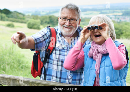 Senior Couple Hiking In Countryside Looking Through Binoculars Stock Photo
