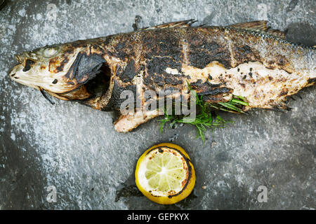 High angle view of a grilled fish with lemon and herbs. Stock Photo