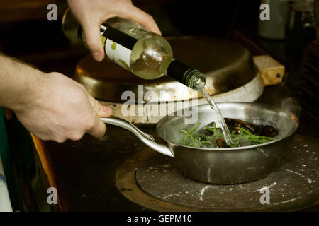 Chef adding white wine to a pan of Black Mussels and samphire.