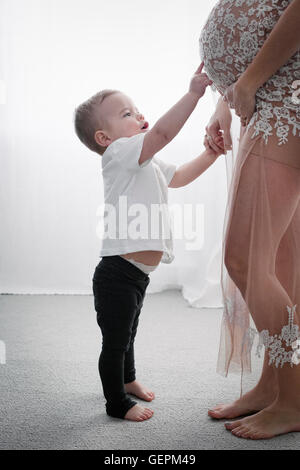 A heavily pregnant woman holding her young son by the hand. Stock Photo