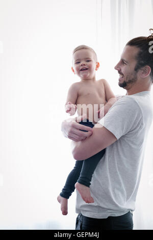 A young man holding a small child in his arms. Stock Photo