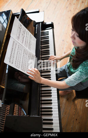 Young woman playing on a grand piano in a rehearsal studio. Stock Photo