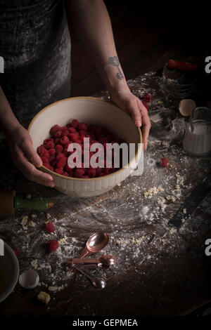 Valentine's Day baking, woman preparing fresh raspberries in a bowl. Stock Photo