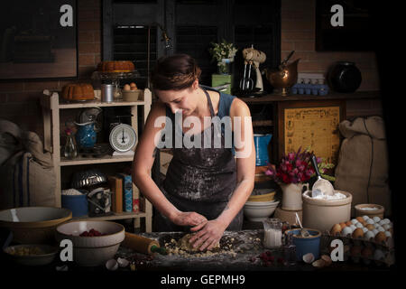 Valentine's Day baking, young woman standing in a kitchen, preparing dough for biscuits. Stock Photo