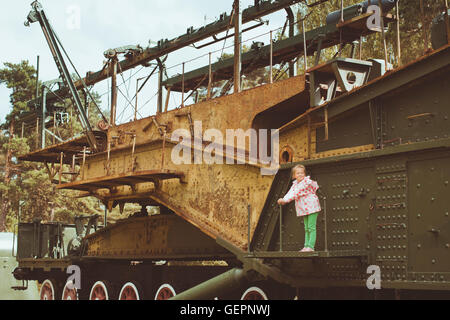 Girl in a pink jacket on a 305-mm installation TM-3-12 on the military-historical site of Fort Krasnaya Gorka, Russia Stock Photo