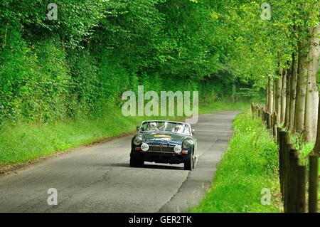 MGB roadster driven by mature couple on classic car summer rally in the south of England Stock Photo
