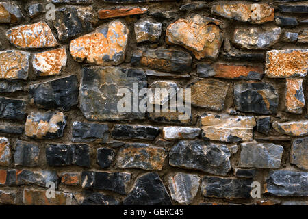 Stone texture of granite wall for the background. Dark monolithic stones joined with cement in a single stone panel. Greek Stock Photo