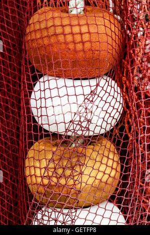 Red fishing net with white, orange and yellow corks in Santona harbour, Cantabria, Spain. Vertical image. Stock Photo