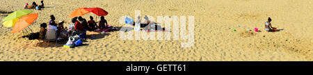 A family group sits on the sand whilst on  holiday at Margate Beach in Kent Stock Photo