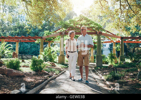 Full length portrait of happy senior couple walking together in a city park. Mature man and woman on a vacation. Stock Photo