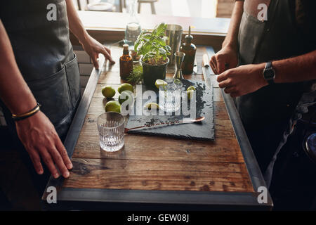 Close up shot of two male barmen preparing new cocktail recipe. Bartenders standing with accessories and ingredients on the coun Stock Photo
