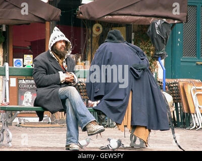 Eccentric character sitting on bench in Place du Marché Ste-Catherine, le Marais, Paris, France Stock Photo