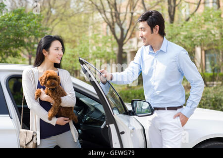 Young Chinese couple getting out of car with their pet dog Stock Photo