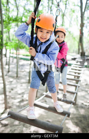 Happy Chinese children playing in tree top adventure park Stock Photo