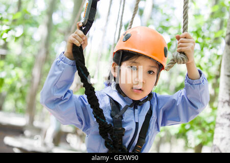 Little Chinese girl playing in tree top adventure park Stock Photo