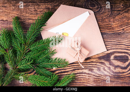 Envelope and blank card for holiday message on wooden background, craft handmade gift box decorations viewed from above Stock Photo