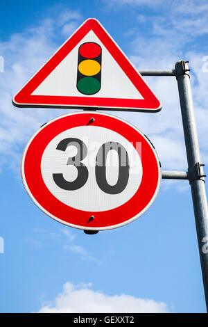 Traffic lights and speed limit 30 km per hour are on one metal post. Road signs over blue sky background Stock Photo