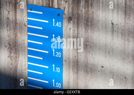 Blue tide level measurement scale on concrete mooring wall in port Stock Photo