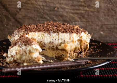 Tiramisu cake and spoon on dark plate with wooden background Stock Photo