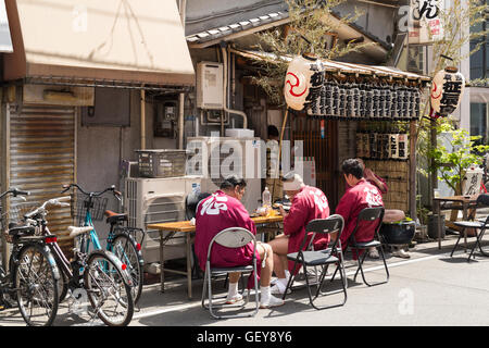 Three men take a break at a small restaurant during the sanja matsuri before continuing with the parade. Asakusa, Tokyo, Japan Stock Photo