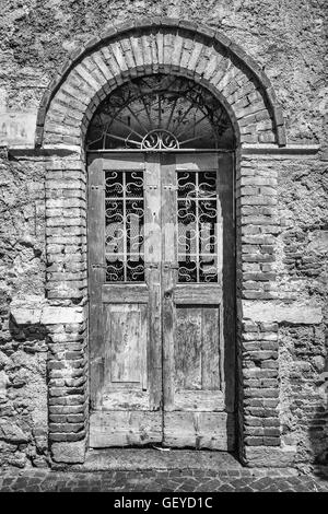 Old wooden door with upper railing and brick archway. Stock Photo