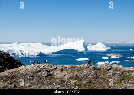 People on a hiking trail at Nakkaavik viewpoint overlooking Disko Bay with icebergs from Ilulissat Icefjord offshore. Ilulissat Greenland Stock Photo