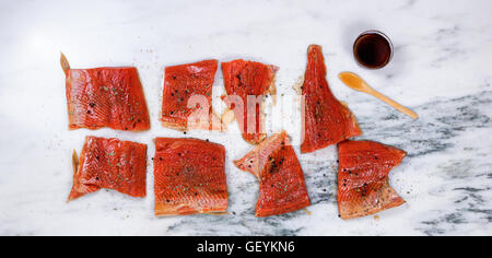 Overhead view of a raw red salmon fillets with seasonings and maple syrup on natural marble stone counter. Stock Photo