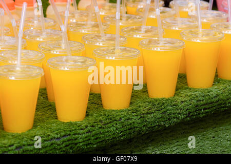 Orange juice in plastic cups with straws for sale at market stall Stock Photo