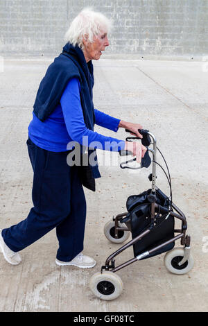 An Elderly Woman Walking With A Rollator Walking Aid, Rottingdean, Sussex, UK Stock Photo