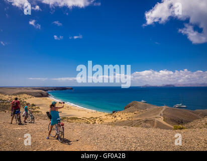 People on bicycles admiring the view of Playa Mujeres in Lanzarote, Canary Islands, Spain. Picture taken 20 April 2016. Stock Photo