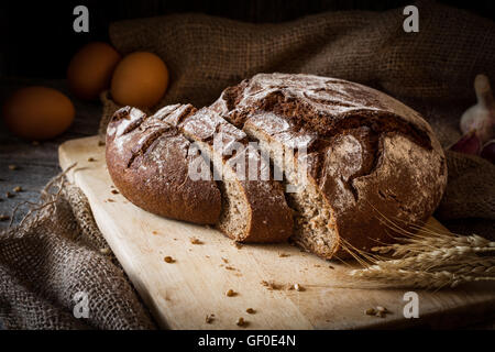 Sourdough rye bread sliced on wooden cutting board. Rustic still life. Natural light, low key
