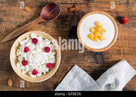 Dairy products: fresh yogurt and cottage cheese with raspberry and fruit on wooden background. Top view Stock Photo