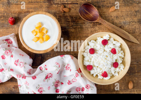 Fresh cottage cheese and yogurt in bowl with fruits and raspberry on wooden background. Overhead view. Dairy products Stock Photo