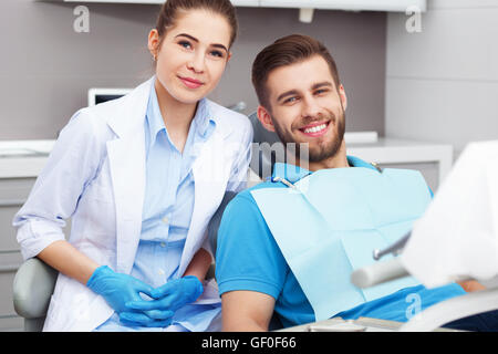 My dentist is the best! Portrait of a female dentist and young man in a dentist office. Stock Photo