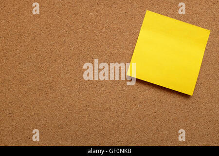 Yellow sticky note stuck on corner of cork pin board with copy space Stock Photo