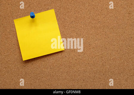 Blank yellow note paper pinned to a cork notice board with copy space Stock Photo
