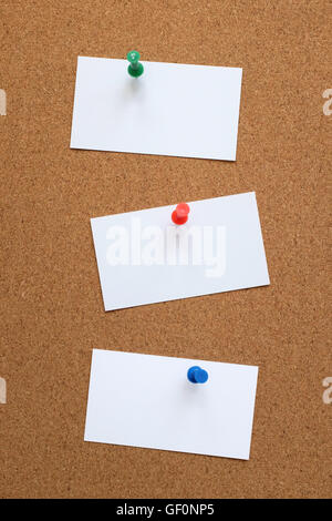 Three blank business cards pinned to a cork pin board Stock Photo