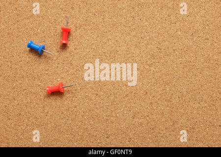 Three drawing pins on an empty cork noticeboard with copy space Stock Photo