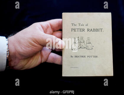 A member of staff holds a first issue of The Tale of Peter Rabbit, estimated at &pound;25,000-35,000, which will be auctioned in the Beatrix Potter Books and Works on Paper sale on her 150th anniversary at Dreweatts &amp; Bloomsbury Auctions in London. Stock Photo